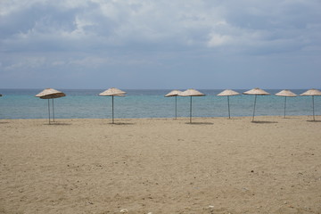 Thatched parasols in an empty beach at sunny day