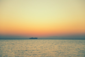 Fototapeta na wymiar cargo ship on horizon at sea sunrise