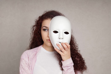 sad young woman hiding her face behind mask, identity or personality concept