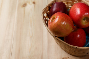 Ripe red apples in a basket on a bright wooden background. Top view