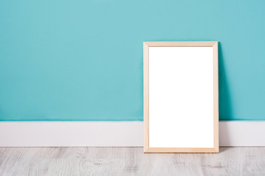 Frame mockup on white wooden floor and turquoise wall. Copyspace.

