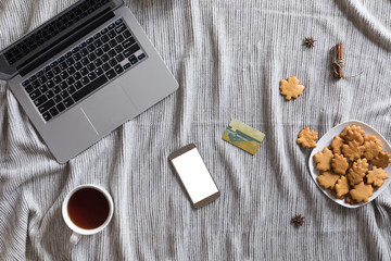 View from above of autumn background with mobile phone, laptop, autumn leaves, cookies, vintage book on white workspace. Top view and flat lay