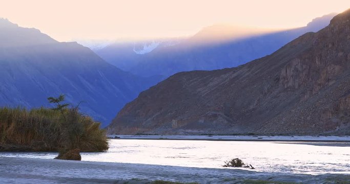 Dreamy landscape of last sun ray glowing above mountain range and reflecting on Shyok river water surface in Nubra valley, Ladakh, India