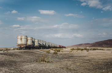 Freight cargo in large white shipping container cylinders being transported via train through the desert of Bolivia