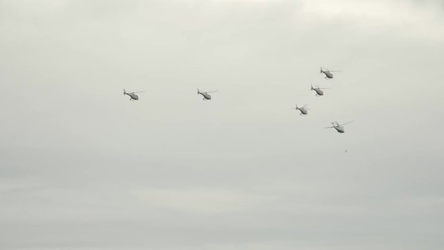 A group of helicopters flying over the sky of small town at cloudy rainy day