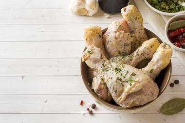 Raw chicken drumstick in marinade with sauce, pepper and herbs. Selective focus.