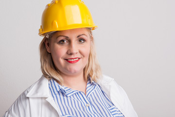 Portrait of an attractive overweight woman with yellow helmet in a studio.
