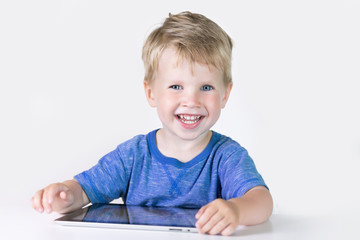 Three years old little kid boy playing children educational or developing games or on the tablet computer at home on white background