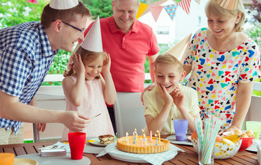 Colorful portrait of happy family celebrate birthday and grandparents blows candles with children