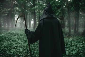 Death with a scythe in the dark misty forest