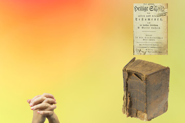 Antique Holy bible and praying hands of a woman in front of bright green color gradient to the reddish background. Concept of religion.