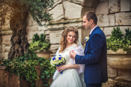 Groom embraces bride behind, outdoors, autumn,