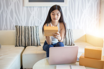 Asian woman is checking the shipping box. And write the address of the recipient. To order online...