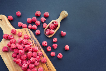 Fresh organic raspberries on black background. berries on a wooden spoon.