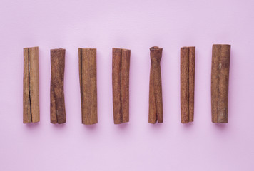 composition of cinnamon sticks on a pink background. Abstract flat pattern, top view