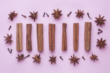 composition of star anise, cinnamon sticks and cloves on a pink background. Abstract flat pattern, top view