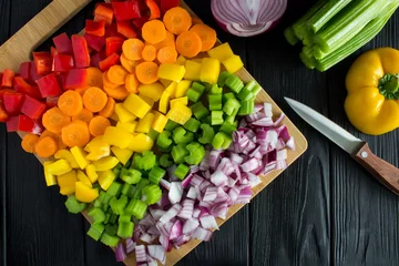 Plexiglas foto achterwand Chopped fresh vegetables  on the cutting board on the black wooden background.Top view. © Liudmyla