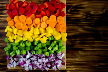 Chopped fresh vegetables  on the cutting board on the brown wooden background.Top view.Copy space.