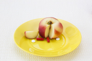 Vitamin concept. Peach and vitamin preparations on yellow disk