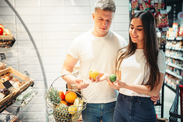 Young couple choosing fresh fruits in supermarket