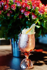 Alcoholic cocktail with ice in bronze glass on bar table.