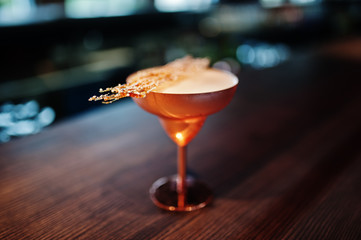 Alcoholic cocktail with fused sugar in bronze glass on bar table.