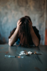 Junkie sitting at the table with drugs and syringe