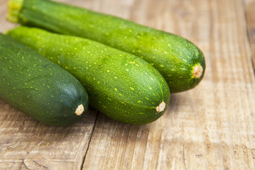 Fresh organic zucchini isolated on rustic wooden background. Summer vegetables, space for text.