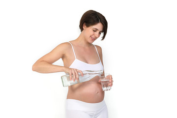 Schwangere Frau schenkt sich ein Glas Wasser ein