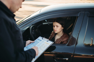 Policeman in uniform writes fine to female driver - obrazy, fototapety, plakaty