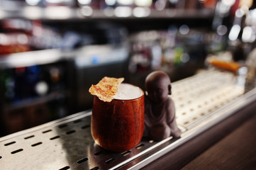 Alcoholic cocktail in wooden cup at  bar table.