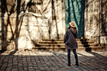 happy and stylish pretty hipster woman holding film photo camera on background of old building  in european city