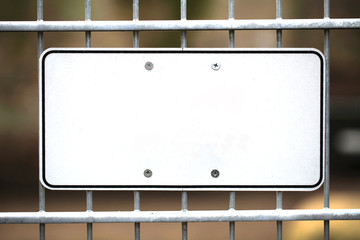 Leeres wei&szlig;es Schild aus Metall an einem Zaun montiert