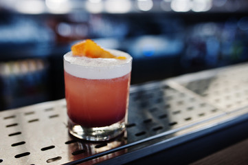 Alcoholic rose cocktail in glass at bar table.