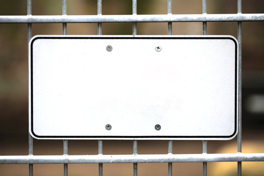 Leeres wei&szlig;es Schild aus Metall an einem Zaun montiert