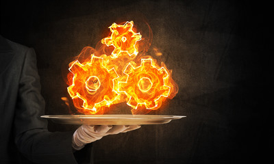 Hand of waitress presenting flaming cogwheels.