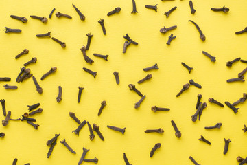 Spices dried cloves on a yellow background. Abstract flat pattern, top view