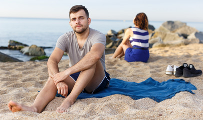 Fototapeta premium Man sitting with displeasure on the beach