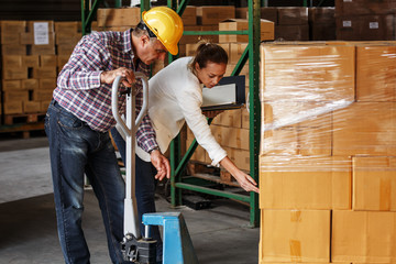 Female manager and warehouse worker checking list and inventory on the shelf in storehouse.