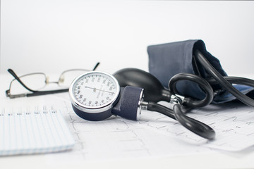 Sphygmomanometer on the working table of a cardiologist. Tonometer, electrocardiogram and notepad...