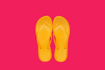 Yellow beach flip flops on neon pink background