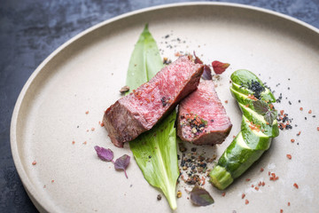 Modern barbecue dry aged sliced fillet steak with wild garlic and baby zucchini as top view on a...