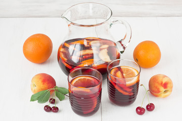 Refreshing red wine sangria drink / Refreshing red wine sangria drink in glasses with orange fruit and peach on white wooden background