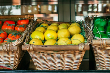 Organic summer collection of vegetables and fruits. Tomatoes, peppers and lemons lie in a wooden basket. The concept for restaurants.