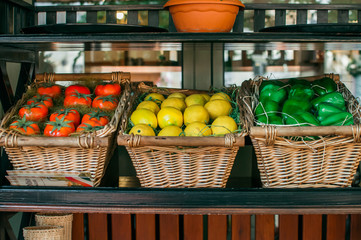 Organic summer collection of vegetables and fruits. Tomatoes, peppers and lemons lie in a wooden basket. The concept for restaurants.