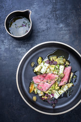 Modern barbecue dry aged sliced fillet steak with asparagus potato salad as top view on a plate