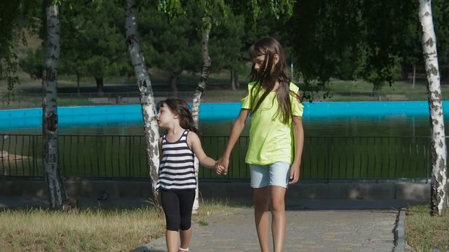 Happy children are walking in the park. Little girls walk together in the park.