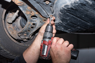mechanic at work. Attach a screw with the cordless screwdriver