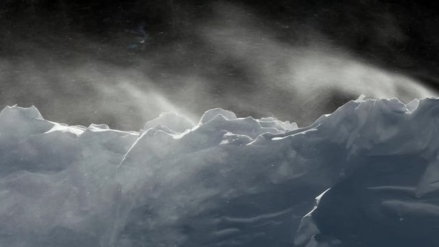 Cold winter wind blows snow over an embankment