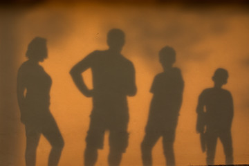 famille en ombre sur mur lors d'un couché de soleil